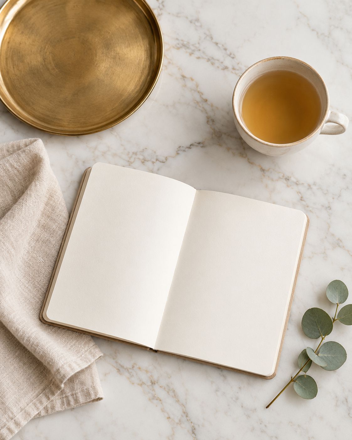 Marble table with tea, a notebook and eucalyptus